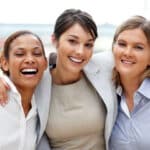 three-women-shoulder-to-shoulder-smiling
